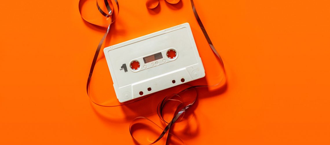 daniel-schludi-mbGxz7pt0jM-unsplash Cassette audio sur fond orange